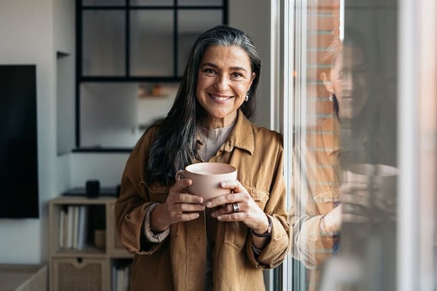 woman smiling at camera holding coffee mug