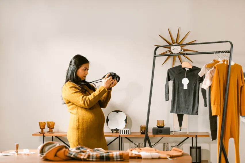 pregnant woman business owner photographing inventory in fashion studio