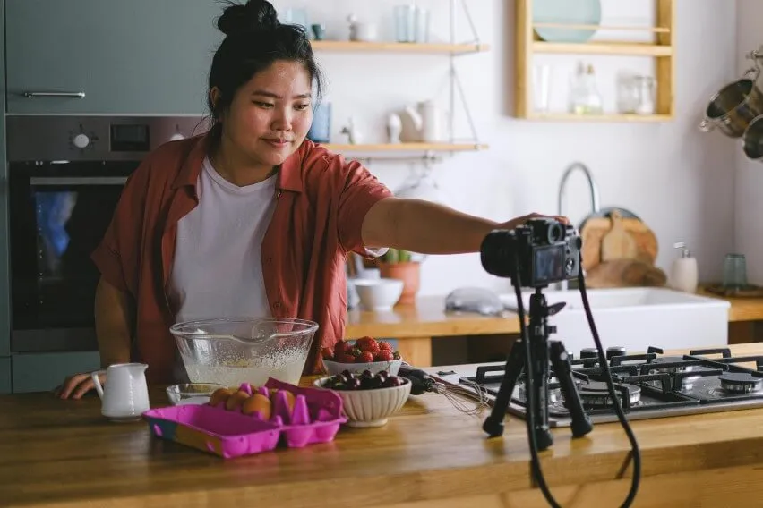 business owner influencer in kitchen adjusting camera for photo shoot